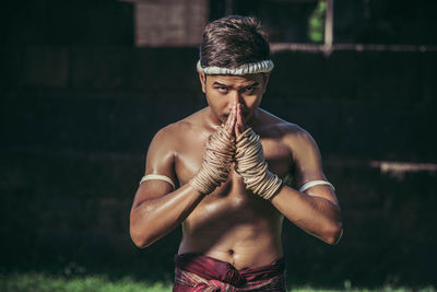 Full length of shirtless man standing against blurred background