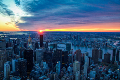 Aerial view of modern buildings in city against sky during sunset