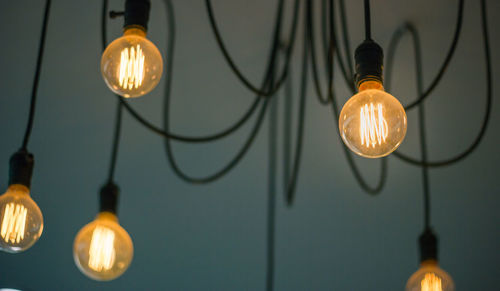 Low angle view of illuminated light bulbs hanging