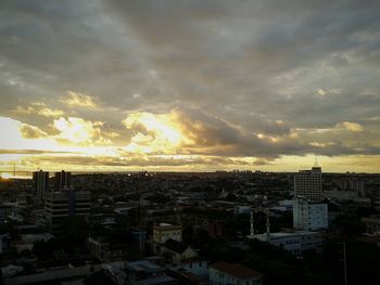 Cityscape against cloudy sky at sunset