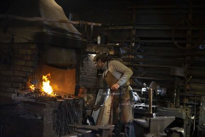 Latvian blacksmith working with open fire in furnace. the blacksmith forging hot iron in workshop