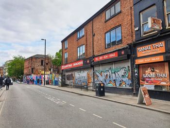 Graffiti on building by street against sky in city