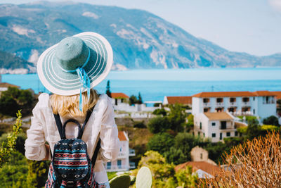 Rear view of woman standing by sea against mountains