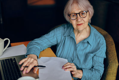 Senior woman with laptop sitting in cafe