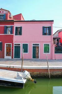 Residential buildings by canal against sky