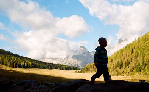 Old fashioned, vintage, film photography on dolomite, little boy play with his wooden ax