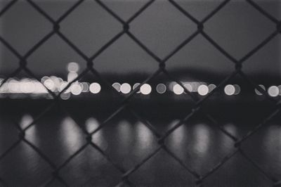 Defocused image of chainlink fence against sky at night