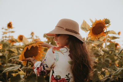 Midsection of woman wearing hat standing against plants