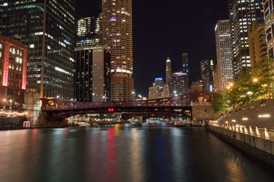 Illuminated buildings by river in city at night