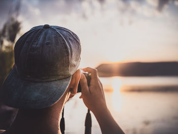 Rear view of man against lake during sunset