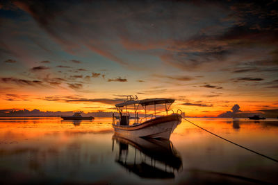 Boat moored in sea against sky during sunset