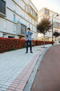 Full length of man walking on sidewalk against building