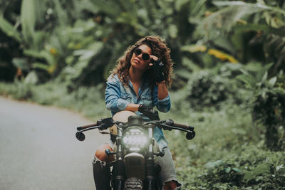 Woman looking away while sitting on motorbike on road