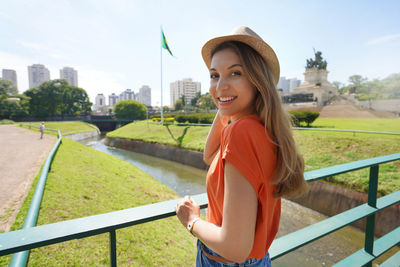 Girl looking at camera with brazilian national flag and sao paulo cityscape on the background,brazil