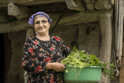 Portrait of smiling young woman standing by plants