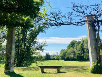 Empty bench in park against sky