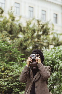 Senior woman photographing through camera in park