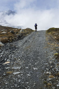 Rear view of man walking on mountain against sky