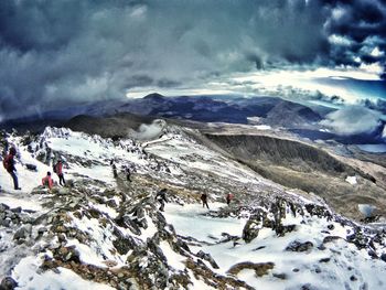 Panoramic view of people on snowcapped mountain against sky
