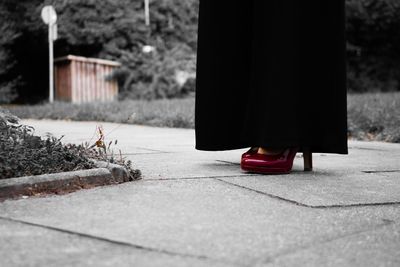 Low section of woman standing on footpath