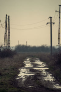 Electricity pylon by road against sky