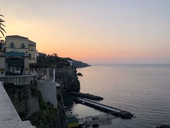 Scenic view of sea and buildings against sky during sunset