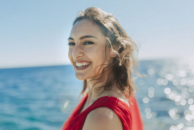 Portrait of smiling young woman against sea