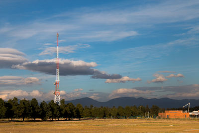 Communications tower on field against sky