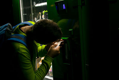 Young man removing money from machine