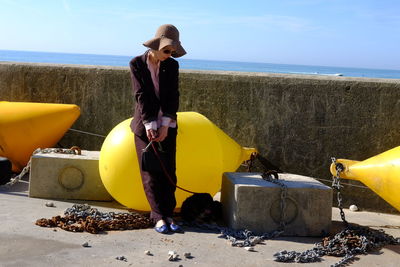 Woman standing by buoys against sky