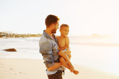 Father and son standing at beach