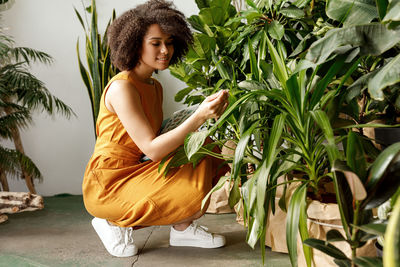 Side view of young woman standing against plants