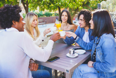 Smiling friends eating breakfast in cafe