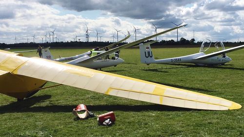 Airplane flying over field against sky