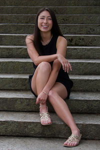 Portrait of a smiling young woman sitting on steps