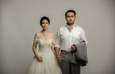 Portrait of young couple standing against wall