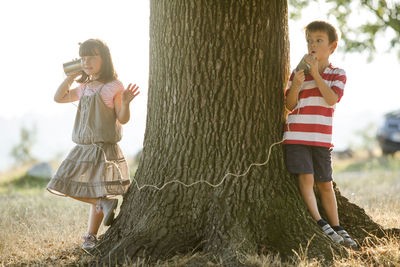 Little boy and girl playing with tin can phone in nature