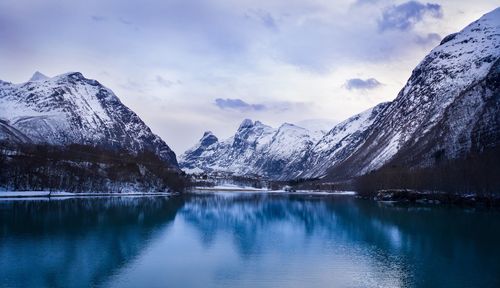 Scenic view of lake by snowcapped mountains against sky