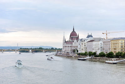 Hungarian parliament building by danube river against sky
