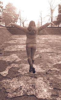 Rear view of woman walking on bare tree