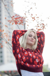 Portrait of young woman standing against buildings and sky