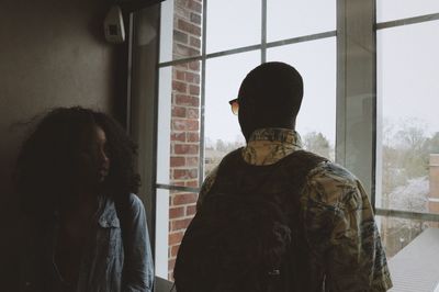 Friends standing by glass window in corridor