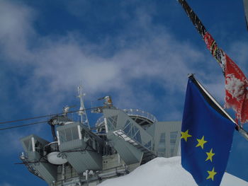 Low angle view of flags hanging amidst buildings against sky