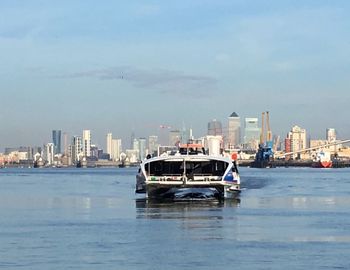Boats in sea by city against sky