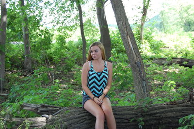 Young woman sitting on log in forest