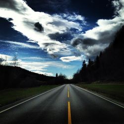 Empty country road against cloudy sky