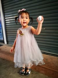 Full length of girl holding toy by closed shutter