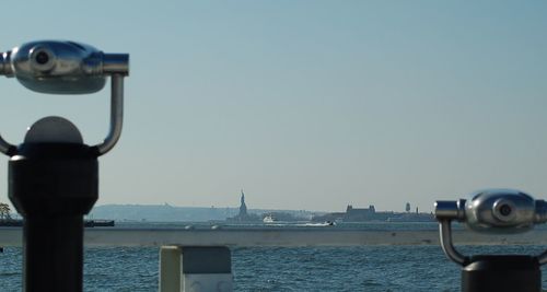 Close-up of coin-operated binoculars by sea against clear sky