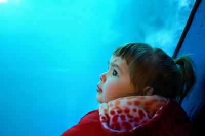 Curious girl looking at fish tank in aquarium