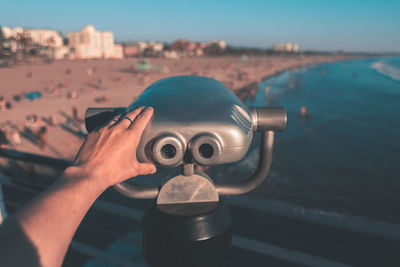 Cropped hand of man holding binoculars in the beach